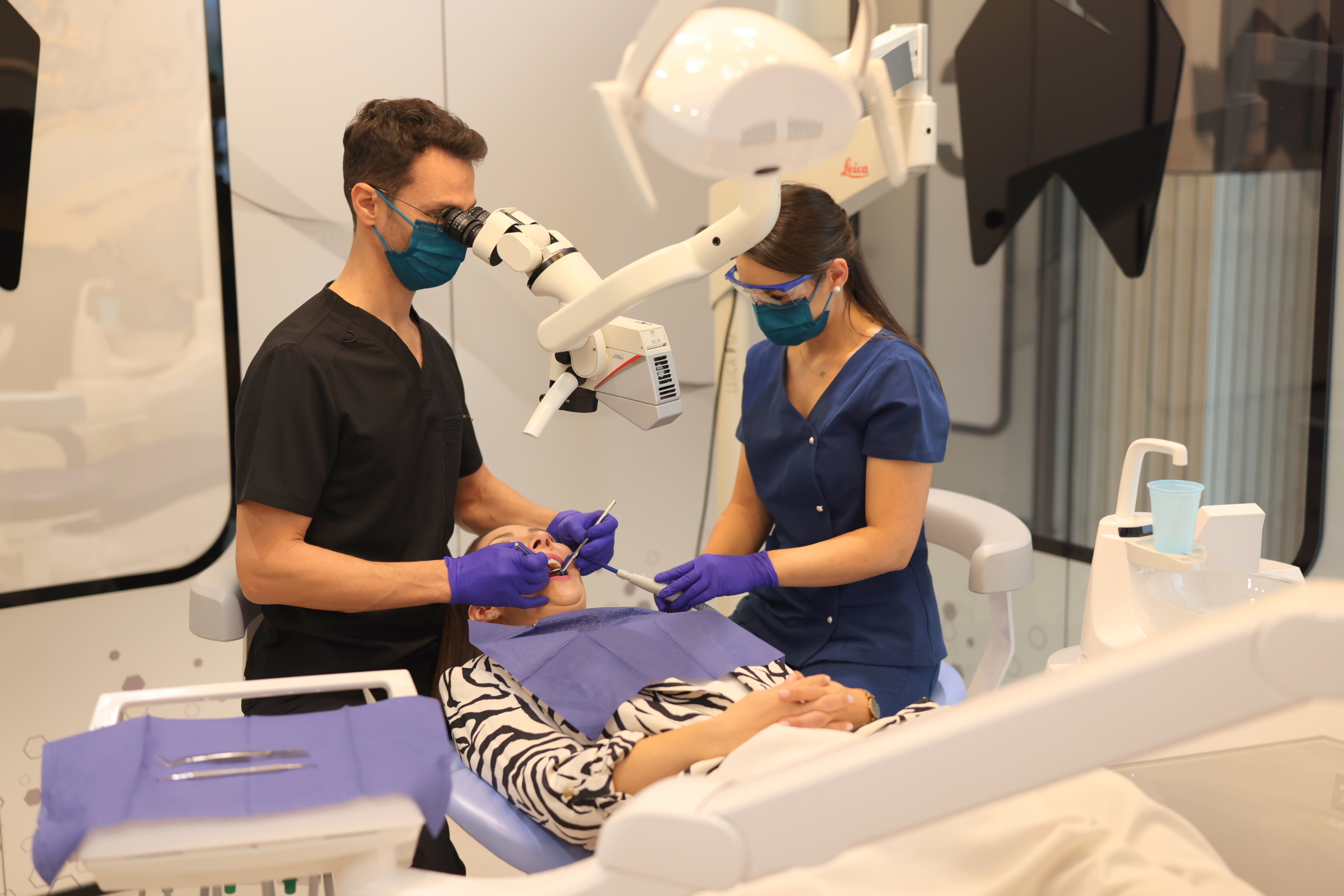 Echipă medicală folosind microscopul dentar în timpul tratamentului de canal